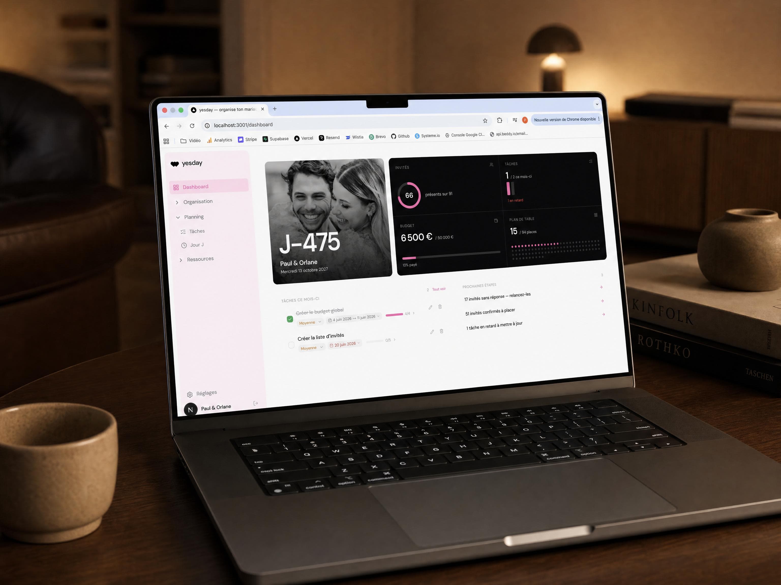 L’appli Yesday ouverte sur un MacBook posé sur un bureau : tableau de bord avec compte à rebours, invités, budget, tâches et plan de table.